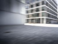 skateboarder performing an trick in a modern city setting with high buildings and cobblestone floor