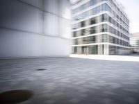 skateboarder performing an trick in a modern city setting with high buildings and cobblestone floor