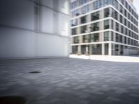 skateboarder performing an trick in a modern city setting with high buildings and cobblestone floor