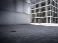 skateboarder performing an trick in a modern city setting with high buildings and cobblestone floor