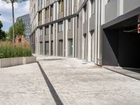 a grey building with some gray bricks on it near tall grass and trees in front