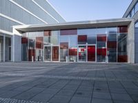 there is a brick walkway leading to the building entry door, with a large white and red sculpture on top