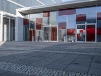 there is a brick walkway leading to the building entry door, with a large white and red sculpture on top