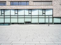 the exterior of an office building with glass on the windows and a brick floor,