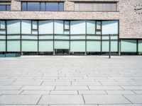 the exterior of an office building with glass on the windows and a brick floor,