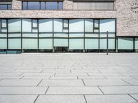 the exterior of an office building with glass on the windows and a brick floor,