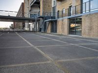 an outdoor walkway leading to an industrial structure with balconies on it and a metal stair case