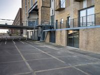 an outdoor walkway leading to an industrial structure with balconies on it and a metal stair case