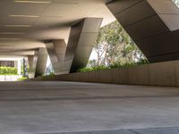 an outside walkway with metal and cement pillars, a bench on one side and a small sidewalk on the other