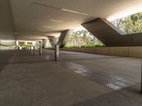 an outside walkway with metal and cement pillars, a bench on one side and a small sidewalk on the other