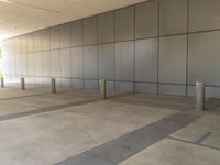 a empty commercial building with a long wall of gray paneled walls with a green pole