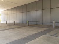 a empty commercial building with a long wall of gray paneled walls with a green pole