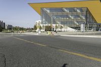 a bus stop at an intersection with a big glass building in the background on the street