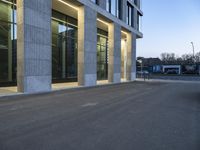 an empty parking lot with light reflecting off glass windows near an office building in the city