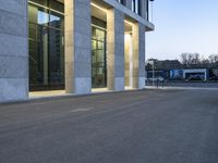 an empty parking lot with light reflecting off glass windows near an office building in the city