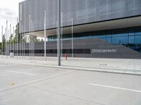 a large building with several metal poles and poles near it are two red fire hydrants and there's an empty parking space