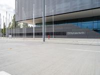 a large building with several metal poles and poles near it are two red fire hydrants and there's an empty parking space