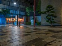 a large brick sidewalk with a store front at night time and a sign that says