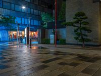 a large brick sidewalk with a store front at night time and a sign that says