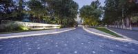 the entrance way to an office building in the evening with trees and landscaping around it