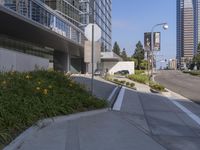 the entrance to an office building with a flower bed area and grass around it, with a black car passing by