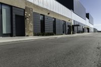 a car driving past the empty commercial building on an empty street in front of a sidewalk