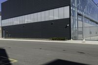 a black building with several windows and some bushes in front of it and a few cars and a white fence