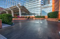 large building with stone floors in large courtyard area by stone columns, plants and a walkway