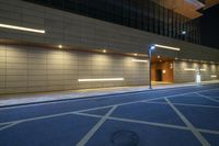 empty street in front of office building at night with clock on wall above parking space