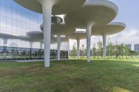 an abstract structure in front of a building near grass and trees in the sunshine light