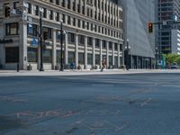 the green paint is painted on a bike path in front of an office building and large, trees