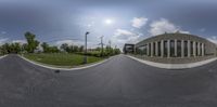 the view from a fish eye lens looking up at the street below the building and a grassy field and trees to the side