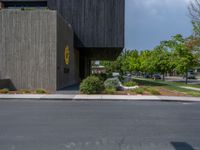 a building with a logo painted on the side near a street that has a sidewalk next to it