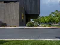 a building with a logo painted on the side near a street that has a sidewalk next to it