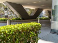 a metal and concrete building with trees and plants in the courtyard area in front of it