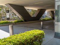 a metal and concrete building with trees and plants in the courtyard area in front of it