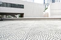 white building with white mosaic pattern in middle of square courtyard with steps leading to other structure