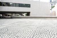 white building with white mosaic pattern in middle of square courtyard with steps leading to other structure