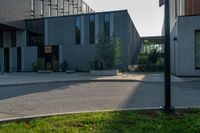 an empty street near a building that has glass windows on it, next to a green grass area