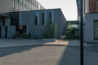 an empty street near a building that has glass windows on it, next to a green grass area