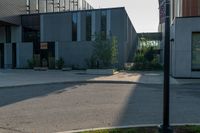 an empty street near a building that has glass windows on it, next to a green grass area