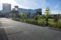 a city street surrounded by grass and tall buildings at the end of a street there is a paved pathway in front of the building