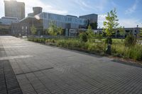 a city street surrounded by grass and tall buildings at the end of a street there is a paved pathway in front of the building