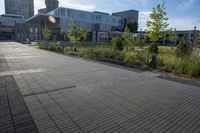 a city street surrounded by grass and tall buildings at the end of a street there is a paved pathway in front of the building