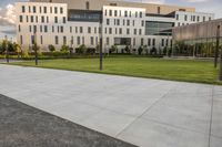 a city street surrounded by grass and tall buildings at the end of a street there is a paved pathway in front of the building