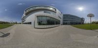 a 360 - view lens of an office building near a field and basketball hoop in the foreground