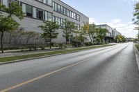 a highway near a building with many windows, and trees lining the side of the road