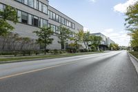 a highway near a building with many windows, and trees lining the side of the road