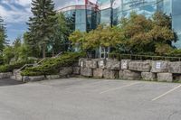 several trees outside of a large office building with rocks around the building's sides