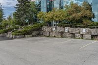 several trees outside of a large office building with rocks around the building's sides